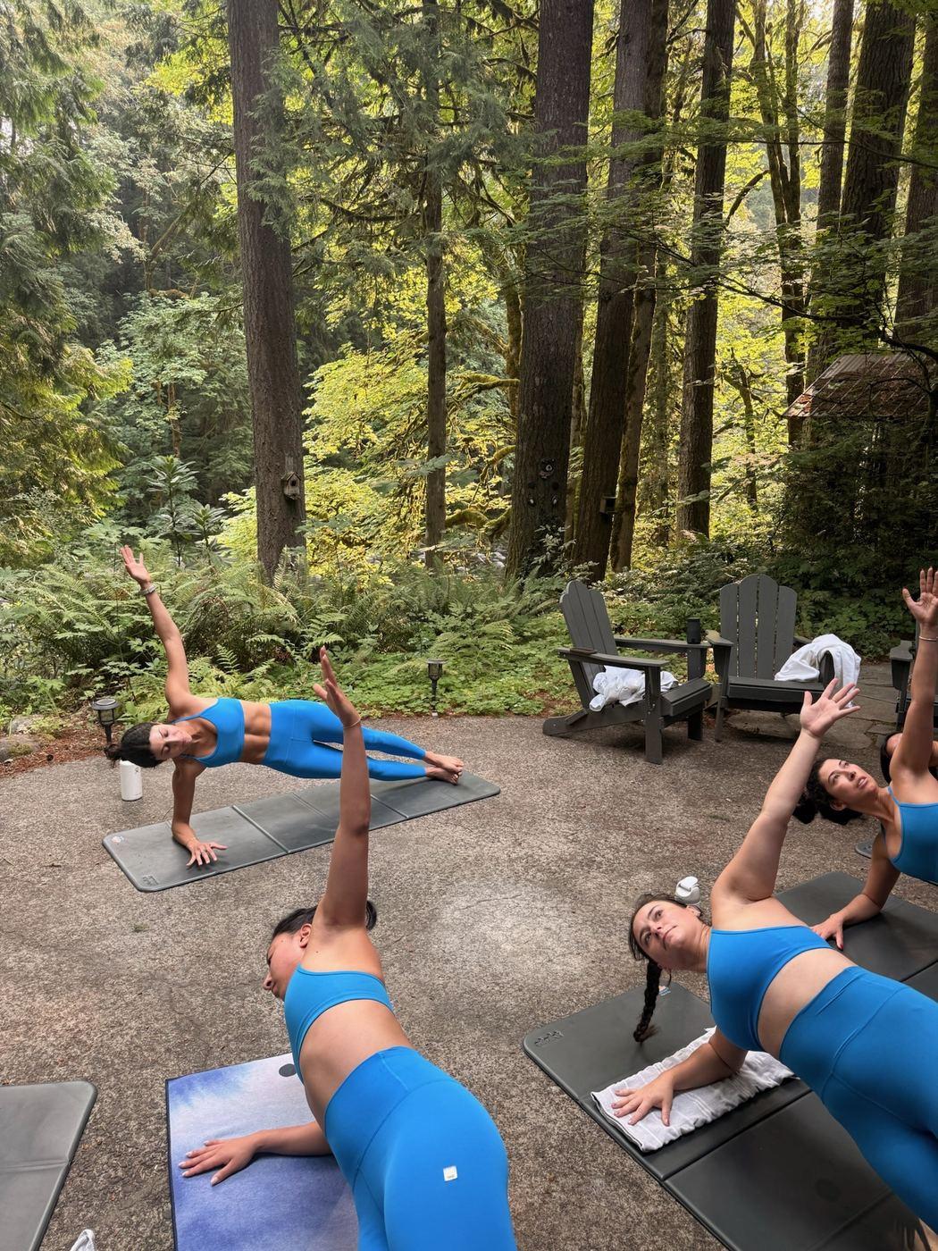 The bachelorette group mid-class, in a side plank pose in the woods