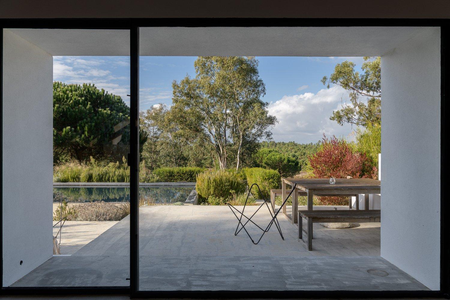 View from indoors out to the pool, terrace, and dining table