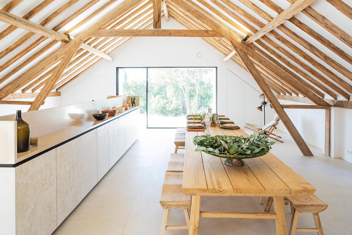 Communal farm-to-table dining area under a wood-beam ceiling